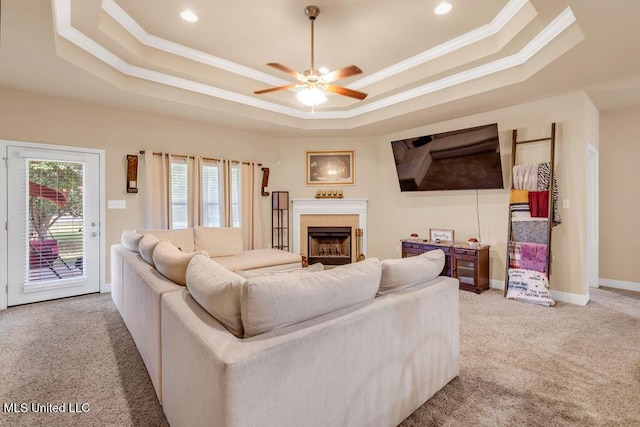 living room with carpet, a raised ceiling, ceiling fan, and ornamental molding