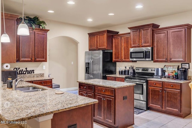 kitchen featuring a center island, arched walkways, light stone counters, a sink, and stainless steel appliances