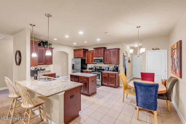 kitchen with a peninsula, a center island, arched walkways, a sink, and stainless steel appliances