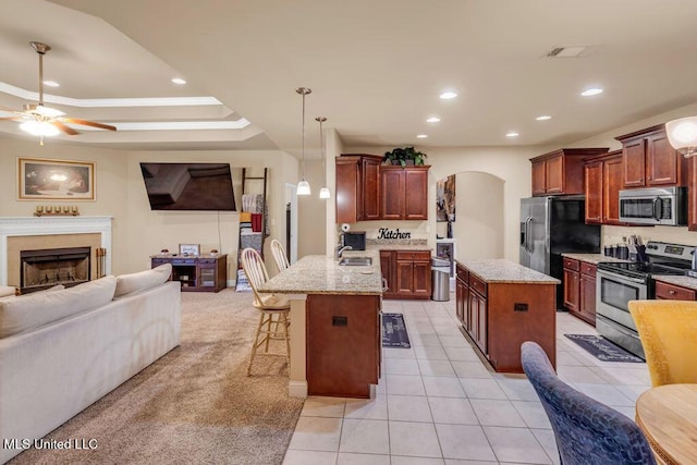 kitchen with ceiling fan, arched walkways, a peninsula, open floor plan, and stainless steel appliances