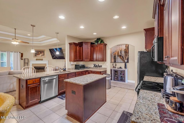 kitchen featuring a peninsula, a kitchen island, a fireplace, open floor plan, and stainless steel appliances