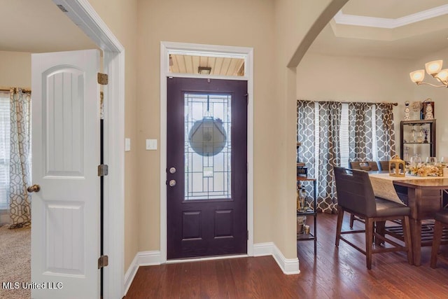 foyer with arched walkways, baseboards, an inviting chandelier, and hardwood / wood-style flooring
