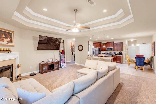 living room with crown molding, a raised ceiling, light colored carpet, and visible vents