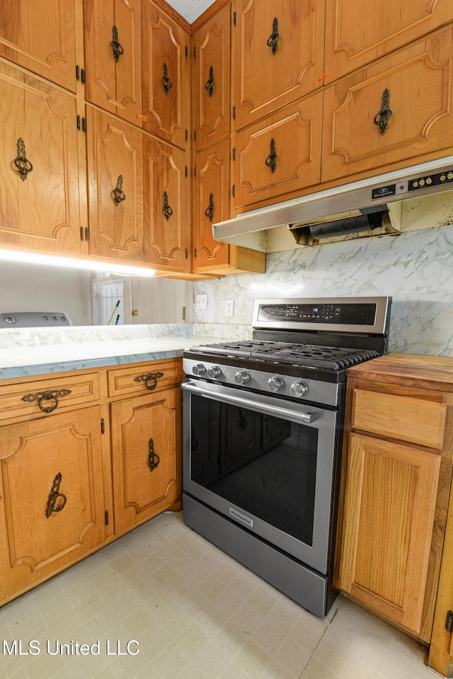 2418 24th Ave, Meridian, MS 39301 - kitchen featuring stainless steel range with gas cooktop, under cabinet range hood, brown cabinetry, tasteful backsplash, and light countertops