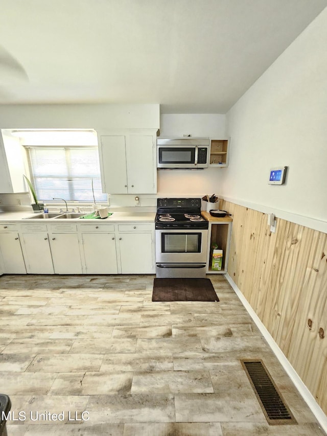 kitchen with visible vents, appliances with stainless steel finishes, a sink, light countertops, and light wood finished floors