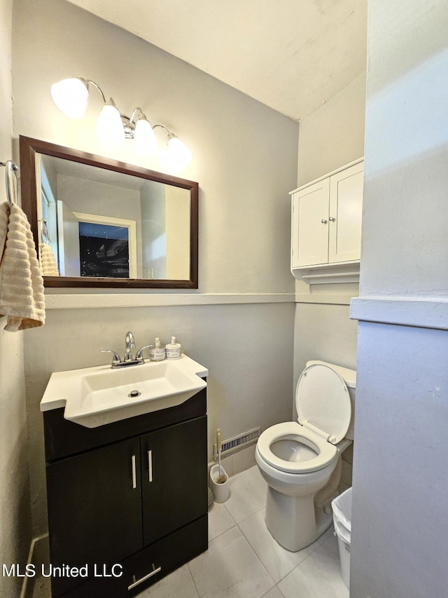 half bathroom with toilet, visible vents, tile patterned flooring, and vanity