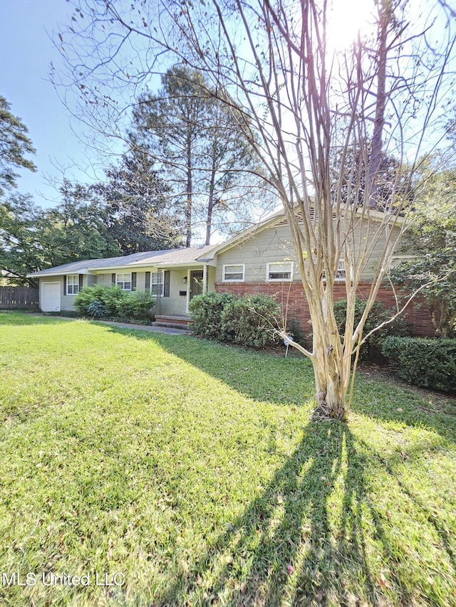 view of front of property with brick siding, an attached garage, fence, and a front lawn