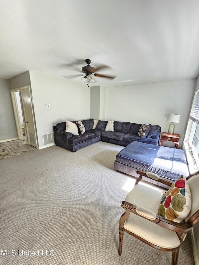 living area featuring carpet floors, baseboards, ceiling fan, and visible vents