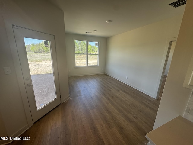 unfurnished dining area with visible vents, baseboards, and dark wood finished floors