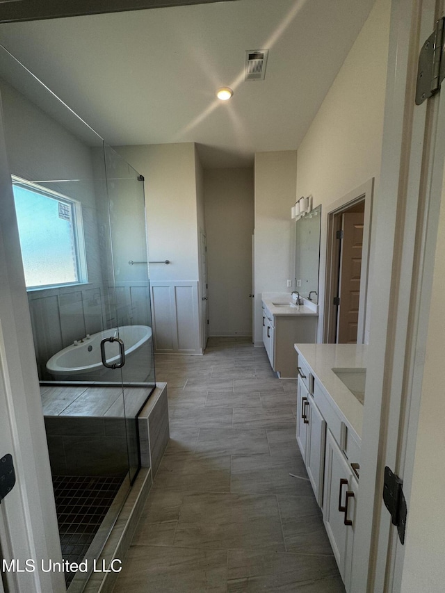 bathroom with visible vents, a sink, a shower stall, a bathtub, and two vanities