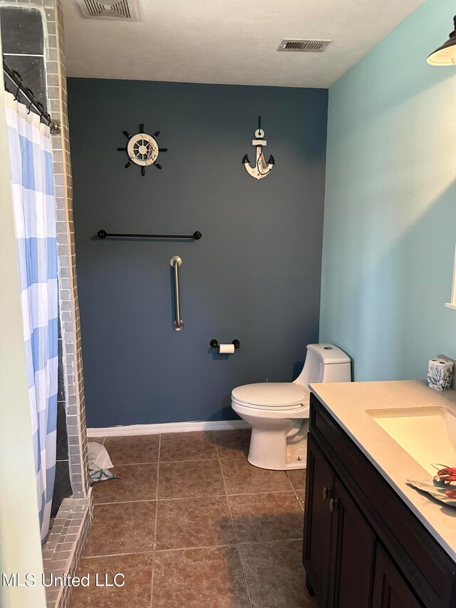 bathroom with toilet, walk in shower, vanity, and tile patterned flooring