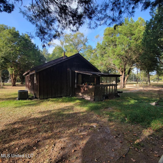 view of side of home with central AC and a yard