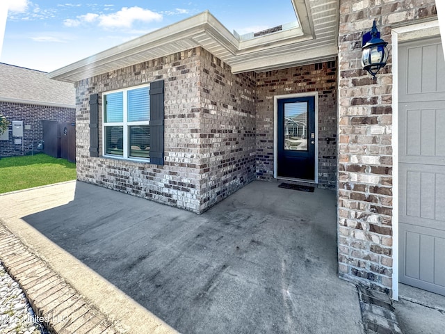 property entrance with a garage and brick siding