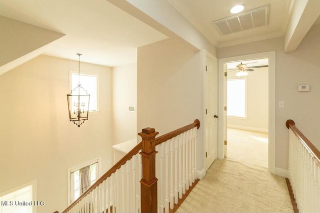 hallway featuring ornamental molding, light colored carpet, and a chandelier