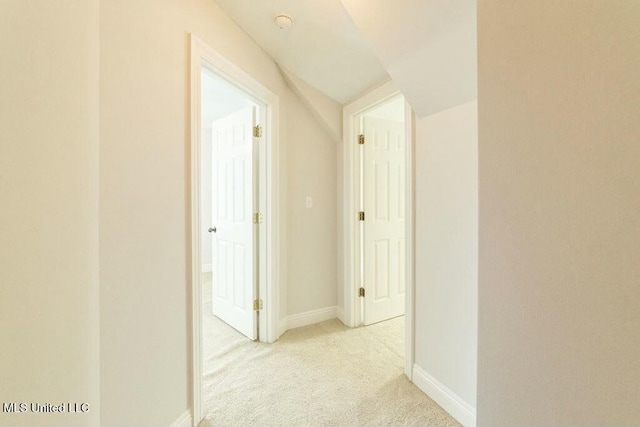 corridor with vaulted ceiling and light carpet