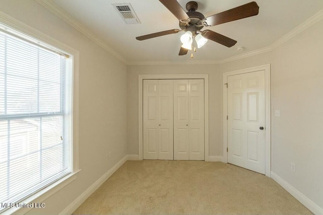 unfurnished bedroom featuring a closet, ceiling fan, ornamental molding, and light colored carpet