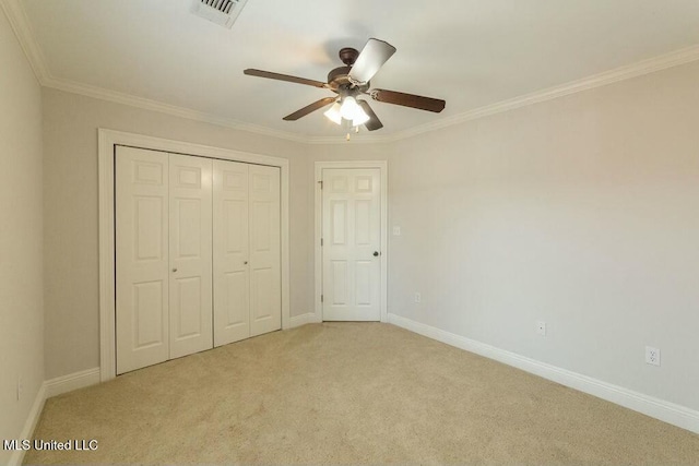 unfurnished bedroom featuring light colored carpet, ceiling fan, crown molding, and a closet