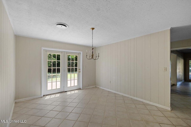 626 N Lexington St, Durant, MS 39063 - unfurnished dining area with baseboards, a chandelier, light tile patterned flooring, a textured ceiling, and wood walls
