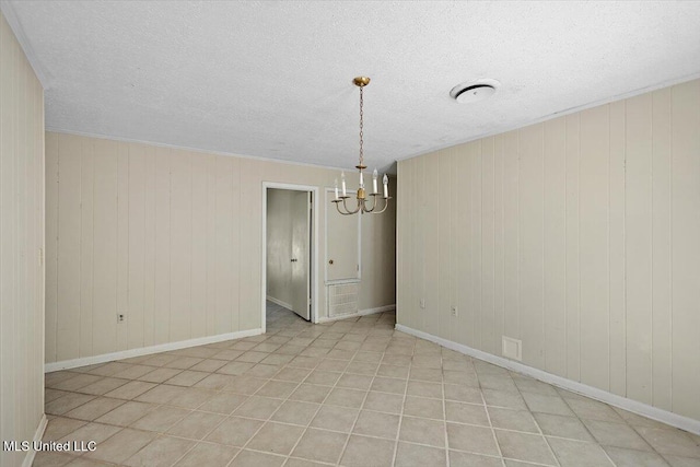 626 N Lexington St, Durant, MS 39063 - spare room featuring a chandelier, a textured ceiling, wooden walls, and baseboards