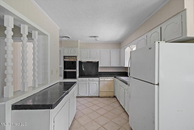 626 N Lexington St, Durant, MS 39063 - kitchen featuring white appliances, a textured ceiling, dark countertops, light tile patterned floors, and white cabinets
