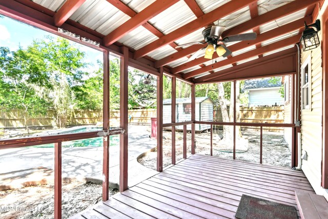 unfurnished sunroom with a wealth of natural light, lofted ceiling with beams, and ceiling fan