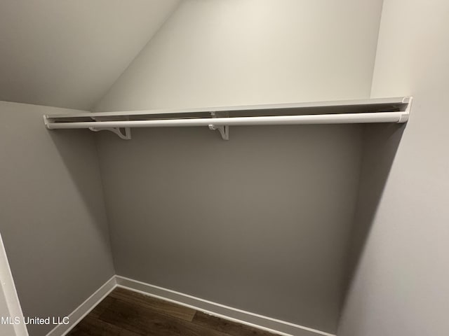 walk in closet with dark wood-style floors and vaulted ceiling