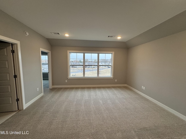 carpeted empty room with vaulted ceiling, baseboards, and visible vents