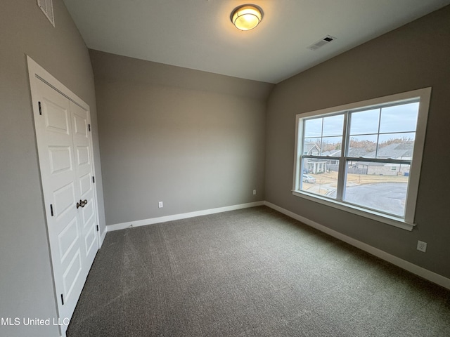 spare room with visible vents, baseboards, and dark carpet