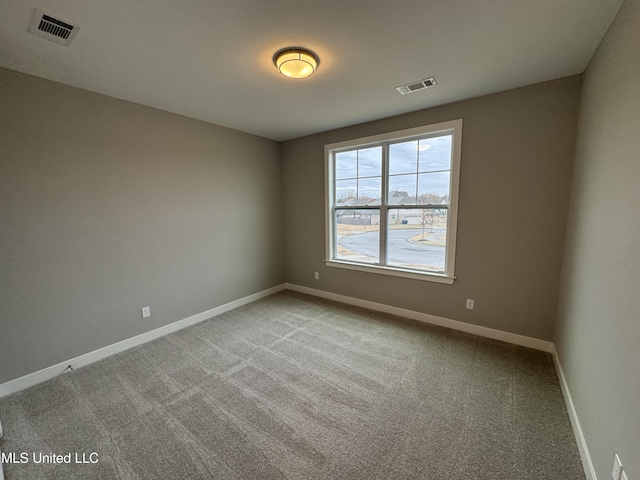 carpeted spare room featuring visible vents and baseboards