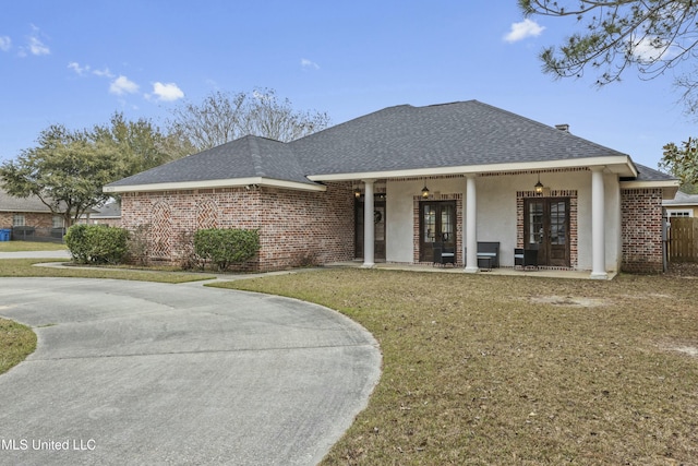 view of front of house featuring french doors, covered porch, and a front yard