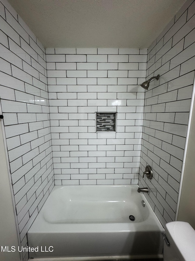 bathroom featuring tiled shower / bath combo and toilet