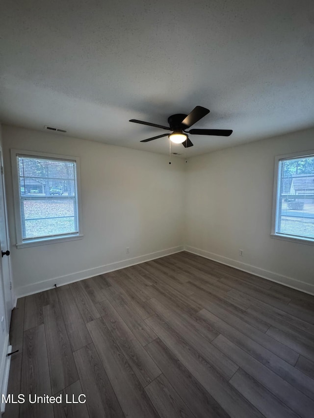 unfurnished room with a textured ceiling, ceiling fan, and dark wood-type flooring