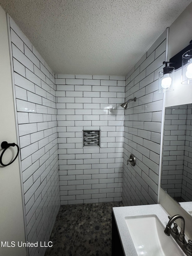 bathroom with vanity, a textured ceiling, and tiled shower