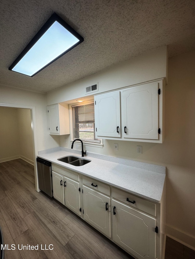 kitchen featuring dishwasher, sink, white cabinets, and light hardwood / wood-style flooring