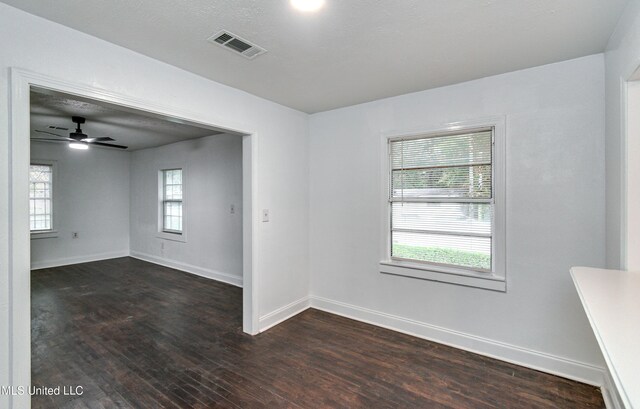 empty room with dark hardwood / wood-style floors, a healthy amount of sunlight, and ceiling fan