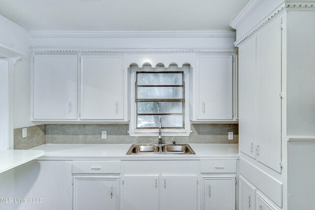 kitchen with decorative backsplash, sink, white cabinets, and crown molding