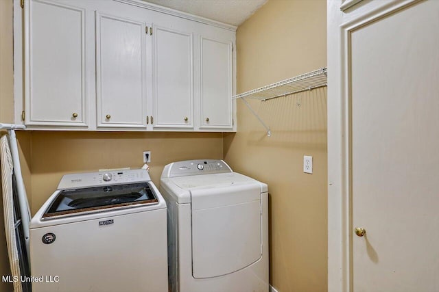 clothes washing area featuring washer and clothes dryer and cabinets