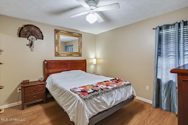 bedroom featuring ceiling fan, hardwood / wood-style floors, and a textured ceiling