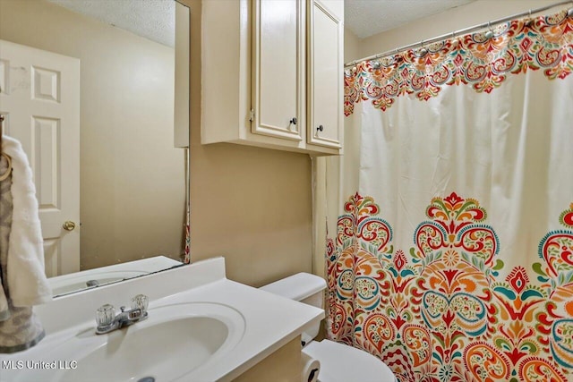 bathroom featuring toilet, a textured ceiling, and vanity