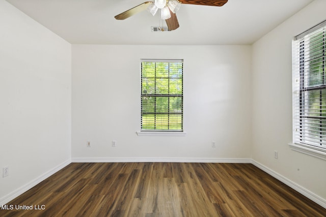 empty room with ceiling fan, a healthy amount of sunlight, and dark hardwood / wood-style flooring