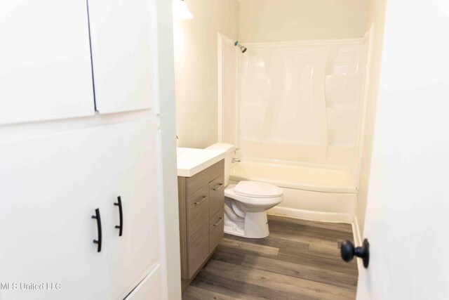 full bathroom featuring hardwood / wood-style flooring, vanity,  shower combination, and toilet