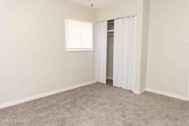 unfurnished bedroom with light carpet and a closet