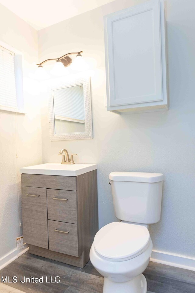 bathroom with hardwood / wood-style floors, vanity, and toilet