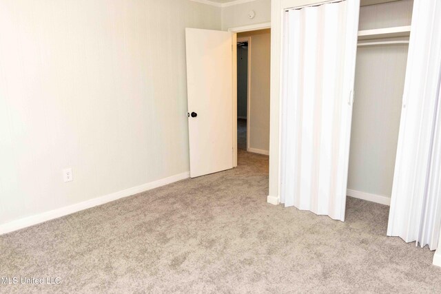 unfurnished bedroom featuring light colored carpet and a closet