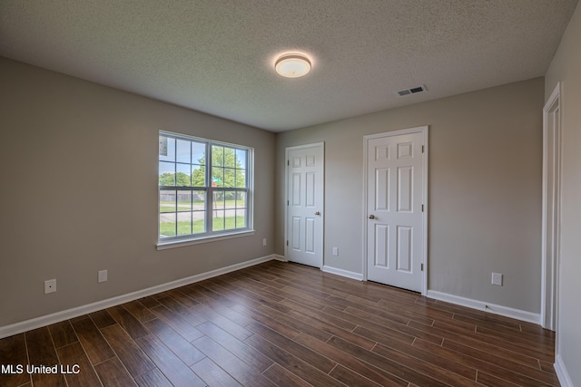 7241 Illinois Central Ave, Horn Lake, MS 38637 - unfurnished bedroom with dark wood finished floors, a textured ceiling, baseboards, and two closets