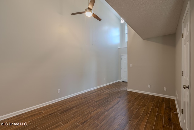 7241 Illinois Central Ave, Horn Lake, MS 38637 - unfurnished room featuring dark wood-style floors, ceiling fan, baseboards, vaulted ceiling, and a textured ceiling