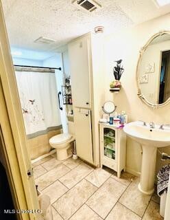 bathroom with tile patterned floors, a textured ceiling, a shower with curtain, and toilet