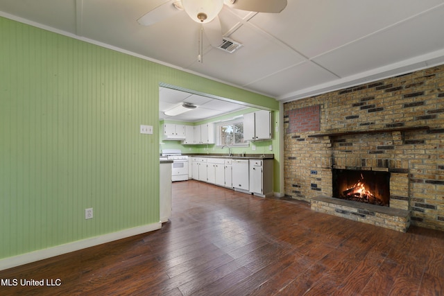 unfurnished living room with ceiling fan, sink, dark hardwood / wood-style floors, and a brick fireplace