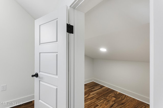 hallway featuring dark wood-type flooring and vaulted ceiling