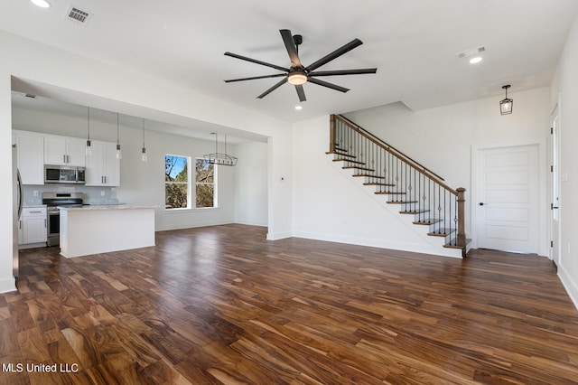 unfurnished living room with dark wood-type flooring and ceiling fan with notable chandelier